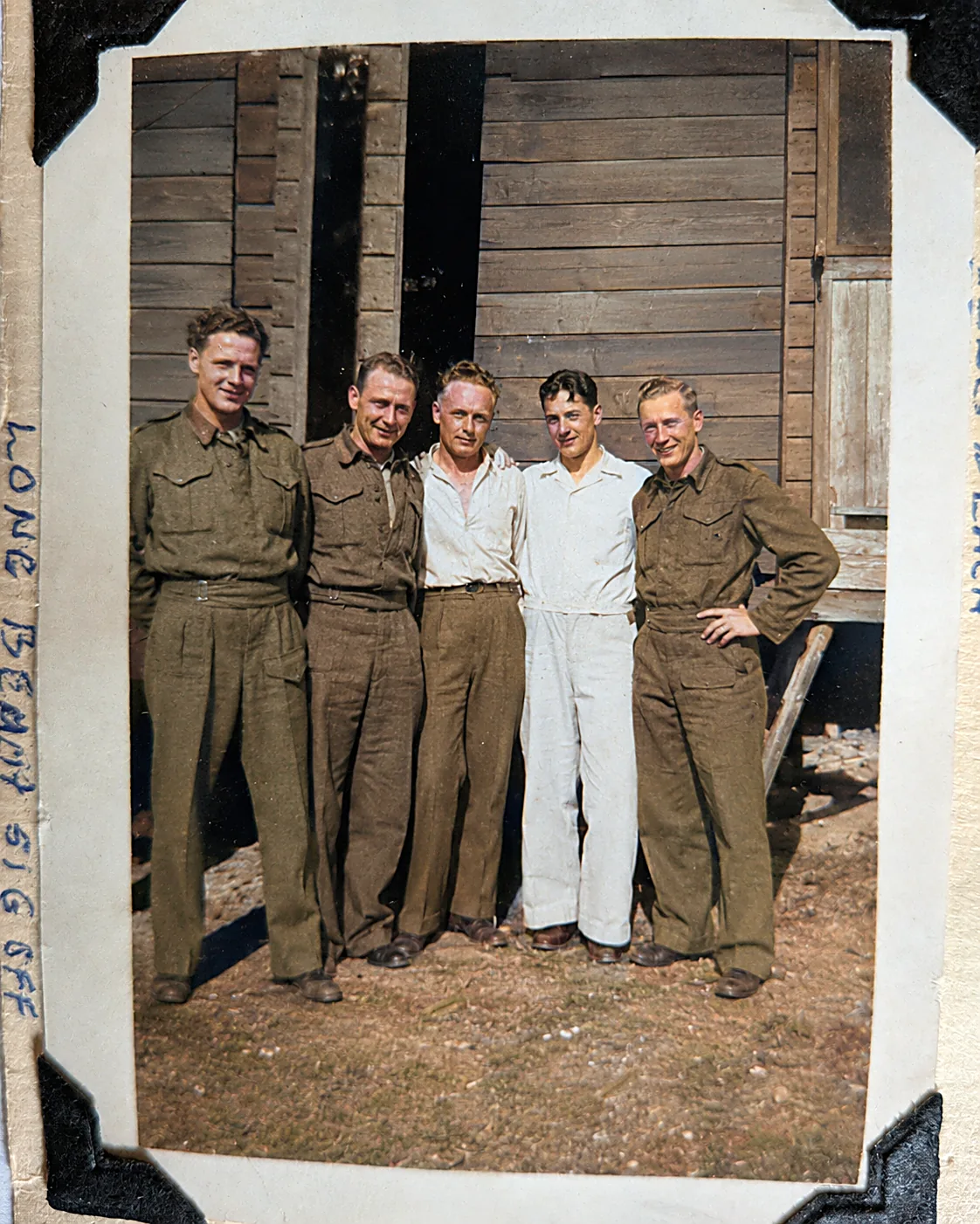 Colourised photograph of five young men, some in uniform and some in civvies, arms over each other's shoulders outside a wooden building. Captioned Long Beach Sig Off.